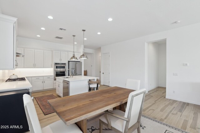 dining area with light wood-style floors, recessed lighting, and visible vents