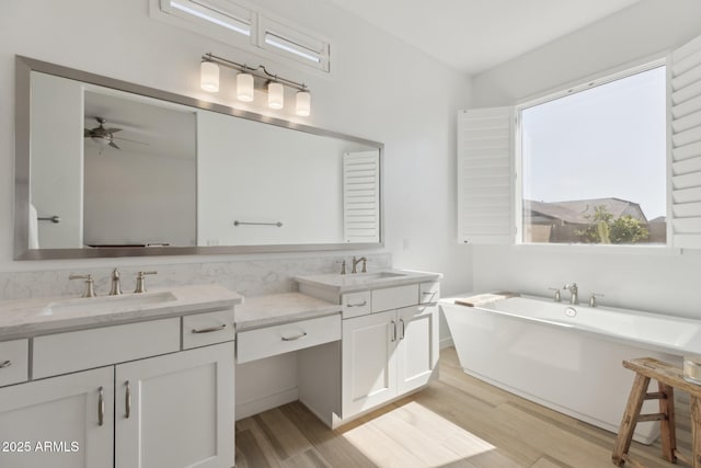 bathroom with wood finished floors, a soaking tub, a sink, and double vanity