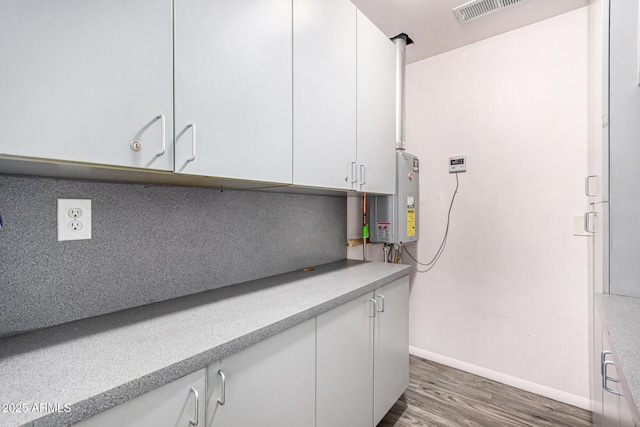 kitchen featuring visible vents, water heater, light countertops, dark wood finished floors, and white cabinets