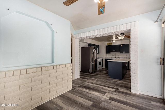 kitchen with freestanding refrigerator, ceiling fan, a breakfast bar area, light countertops, and dark cabinetry