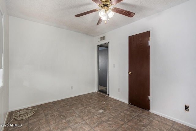 interior space with a textured ceiling, a ceiling fan, visible vents, and baseboards