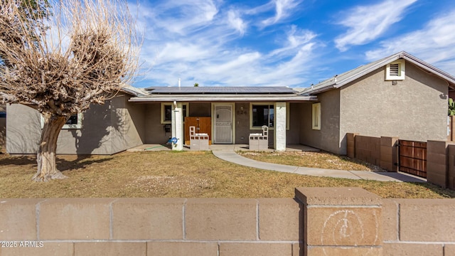 ranch-style house with fence, a porch, stucco siding, and solar panels
