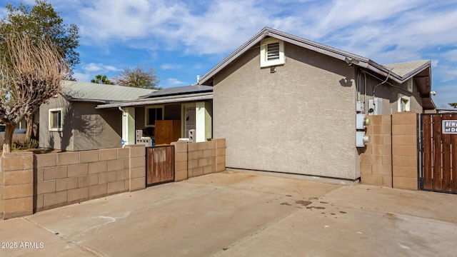 single story home with fence, stucco siding, covered porch, and roof mounted solar panels