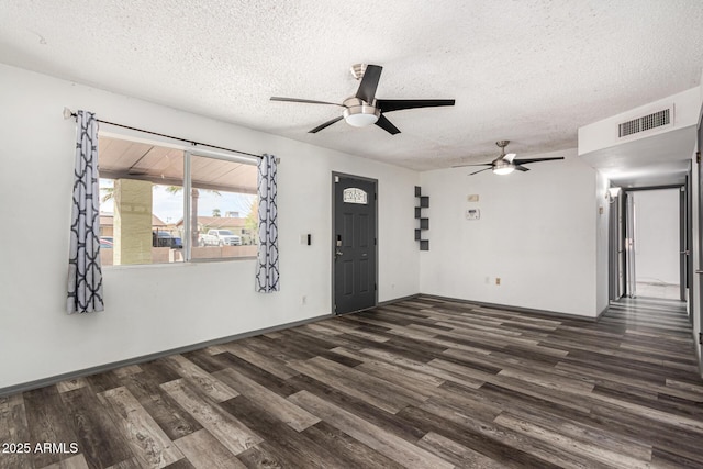 spare room featuring ceiling fan, visible vents, baseboards, dark wood-type flooring, and a textured ceiling