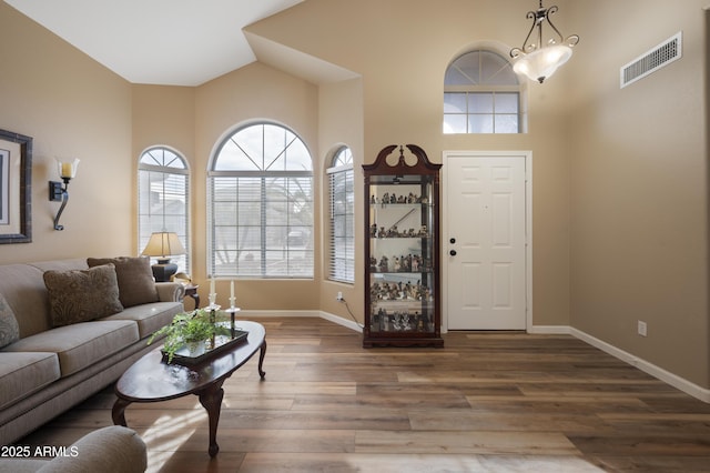 living room featuring high vaulted ceiling, hardwood / wood-style floors, and a notable chandelier