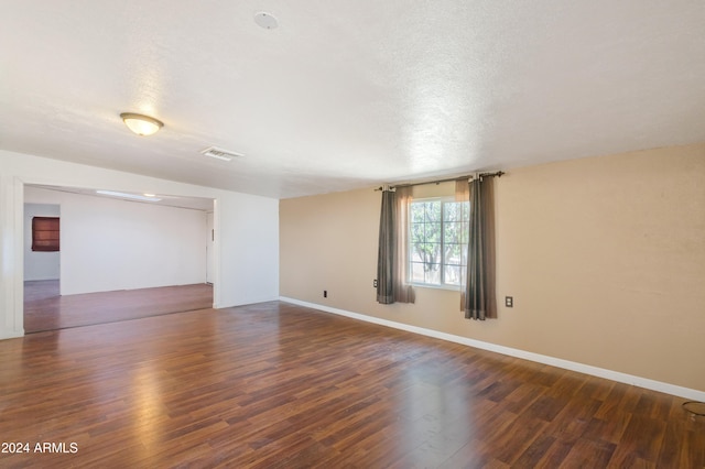 empty room with a textured ceiling and dark wood-type flooring