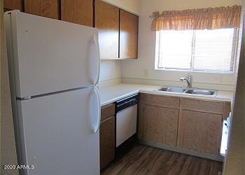 kitchen with dark wood-type flooring, a sink, light countertops, freestanding refrigerator, and dishwasher