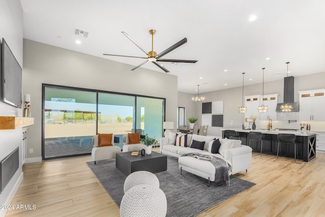 living room featuring ceiling fan with notable chandelier, light hardwood / wood-style floors, and sink