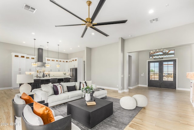 living room with ceiling fan, french doors, and light hardwood / wood-style floors