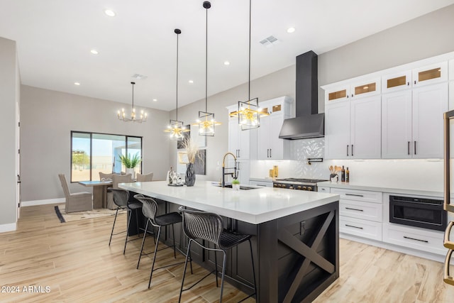 kitchen with sink, white cabinetry, and wall chimney range hood