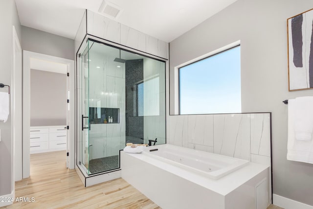 bathroom with hardwood / wood-style floors and shower with separate bathtub