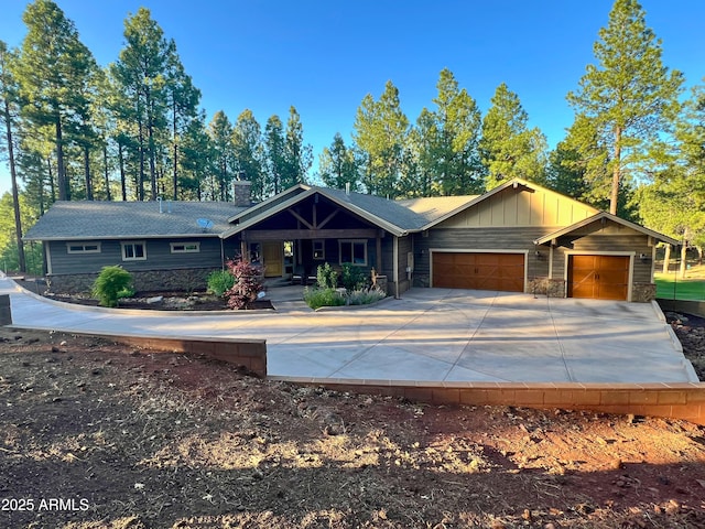 3650 S Bridle Path, Flagstaff, AZ 86005 - view of front facade with a garage, a chimney, concrete driveway, stone siding, and board and batten siding