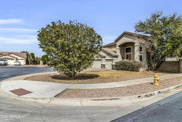 view of front facade featuring driveway, fence, and stucco siding