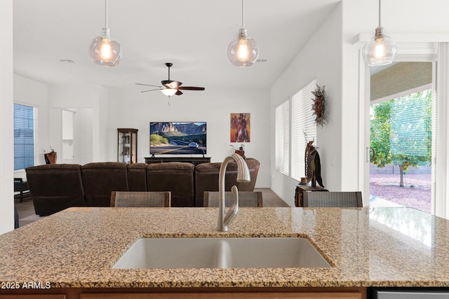 kitchen featuring hanging light fixtures, light stone countertops, and sink