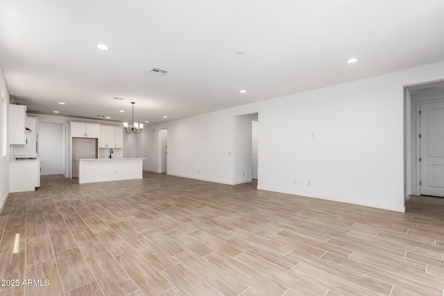 40546 W Michaels Dr, Maricopa, AZ 85138 - unfurnished living room featuring a chandelier, recessed lighting, light wood-style flooring, baseboards, and a sink