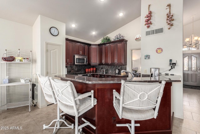 kitchen featuring tasteful backsplash, kitchen peninsula, a breakfast bar, and a chandelier