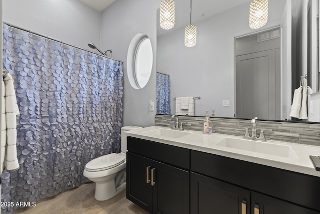 full bathroom with double vanity, wood finished floors, toilet, and a sink