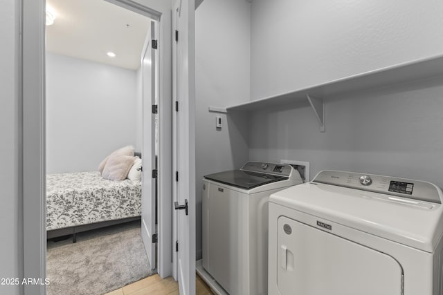 laundry area with light wood-style floors, washer and clothes dryer, and laundry area