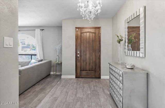 entrance foyer featuring a textured ceiling, light wood-type flooring, and a chandelier