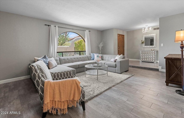 living room with wood-type flooring, a textured ceiling, and a chandelier