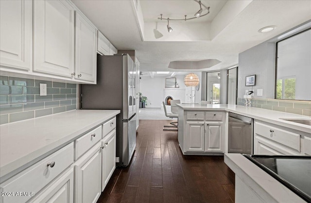 kitchen featuring white cabinets, kitchen peninsula, decorative light fixtures, dark wood-type flooring, and stainless steel appliances