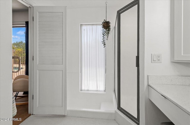 bathroom featuring a shower with shower door, tile patterned flooring, vanity, and a wealth of natural light