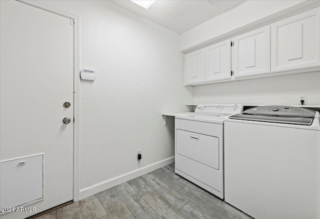 laundry area featuring cabinets, light wood-type flooring, and washing machine and dryer