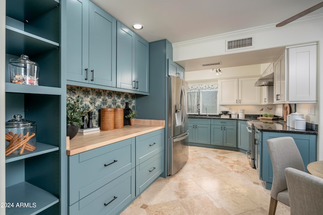 kitchen with light tile patterned floors, ornamental molding, blue cabinetry, appliances with stainless steel finishes, and white cabinetry