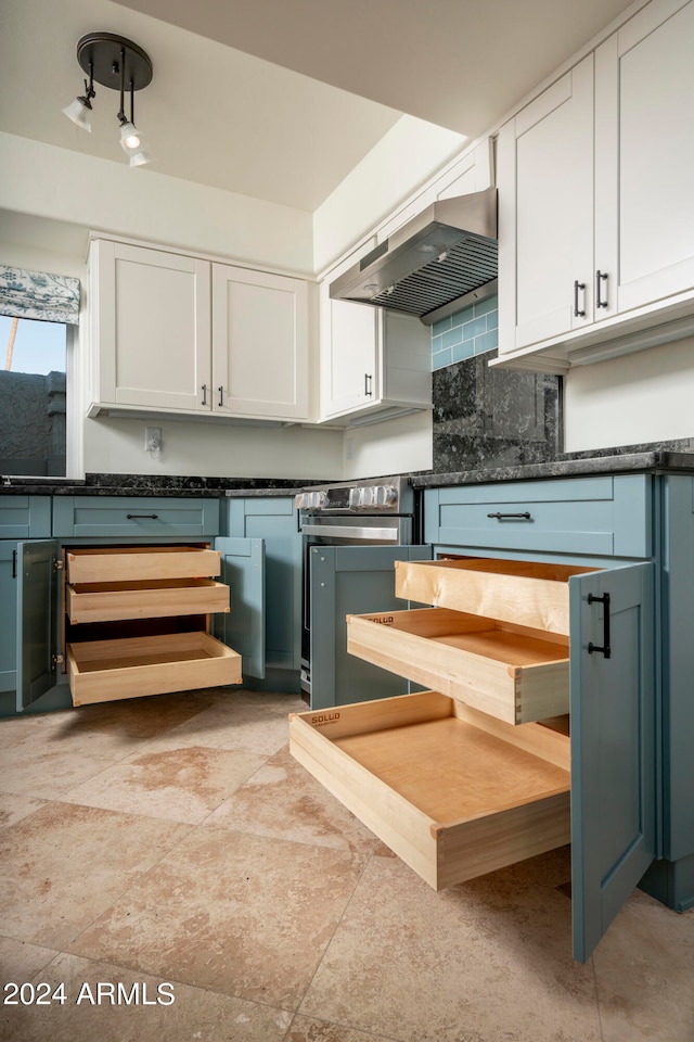 kitchen featuring white cabinets, decorative backsplash, wall chimney exhaust hood, and stainless steel range oven