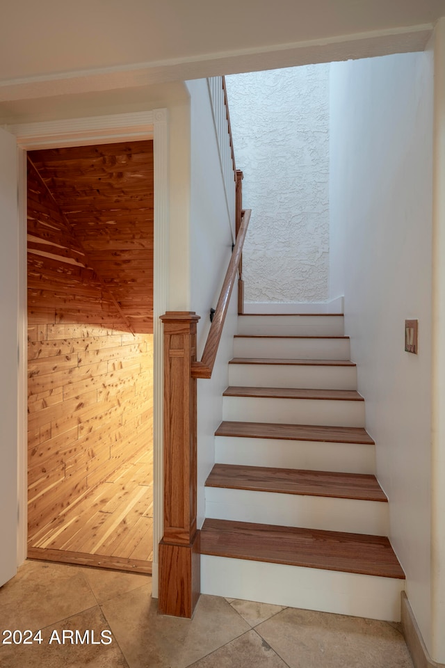 stairway featuring wooden walls and tile patterned flooring