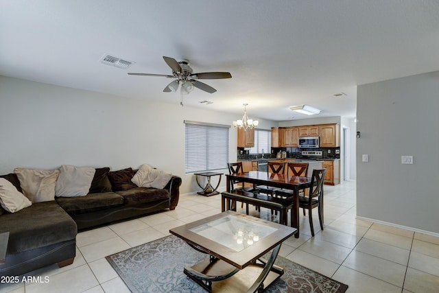 living room featuring light tile patterned floors, visible vents, and ceiling fan with notable chandelier