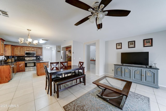 dining space with ceiling fan with notable chandelier, light tile patterned floors, baseboards, and visible vents