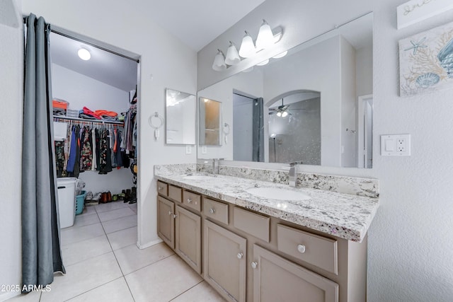 bathroom with a sink, a walk in closet, double vanity, and tile patterned flooring