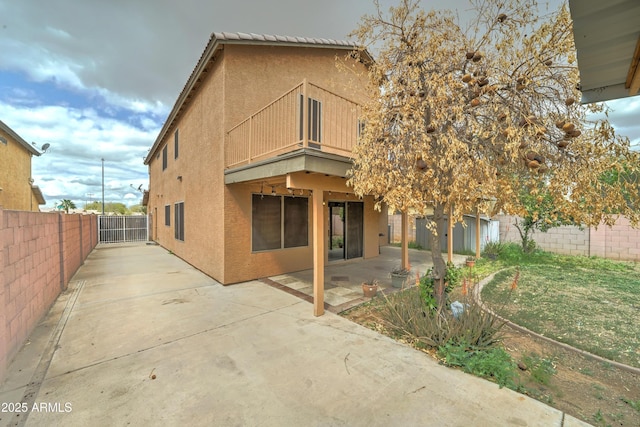 back of property featuring a patio area, a balcony, a fenced backyard, and stucco siding