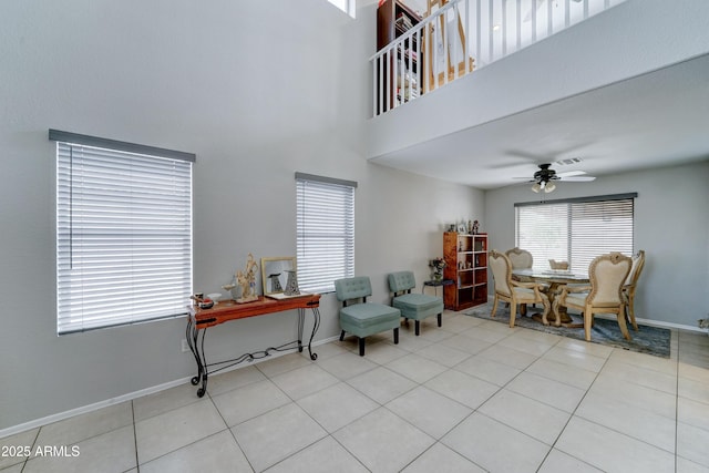 living area featuring baseboards, a towering ceiling, a ceiling fan, and tile patterned flooring