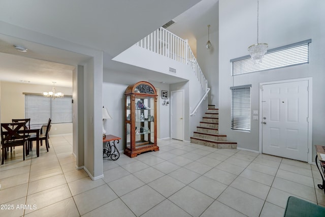 foyer entrance with light tile patterned floors, stairway, visible vents, and an inviting chandelier