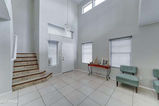 entryway featuring tile patterned floors, stairway, baseboards, and a towering ceiling