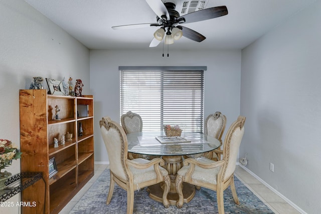 tiled dining area featuring a ceiling fan and baseboards