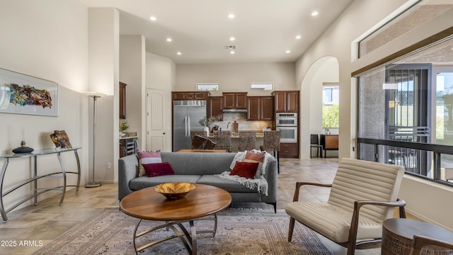 living area featuring arched walkways, a towering ceiling, and recessed lighting