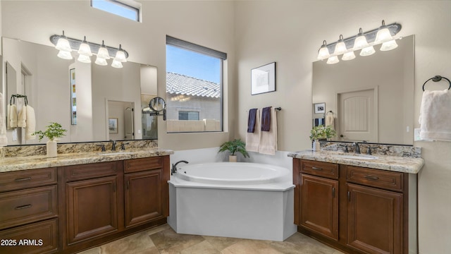 full bath featuring a sink, two vanities, and a bath
