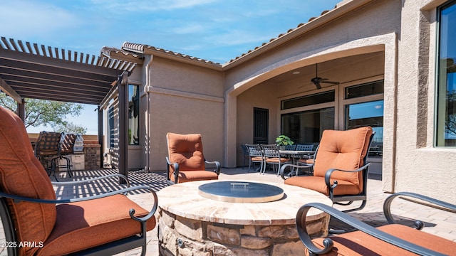 view of patio / terrace featuring a pergola, an outdoor fire pit, outdoor dining space, and a ceiling fan