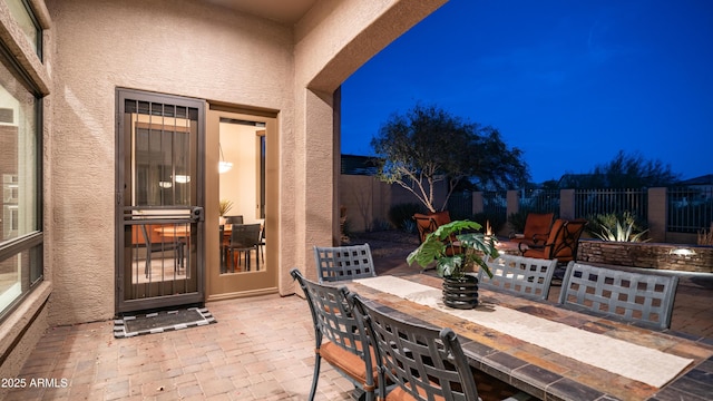 patio at night featuring outdoor dining area and fence