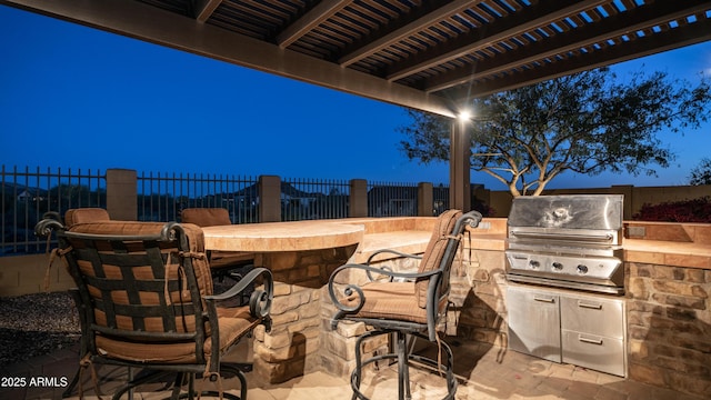 view of patio / terrace with outdoor dry bar, a fenced backyard, exterior kitchen, area for grilling, and a pergola