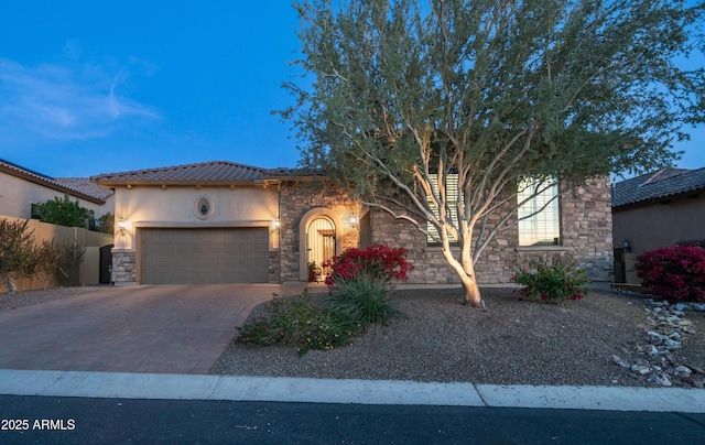 view of front of house featuring driveway, a tile roof, stone siding, stucco siding, and a garage