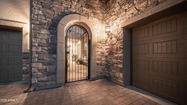 view of exterior entry with stone siding and a garage