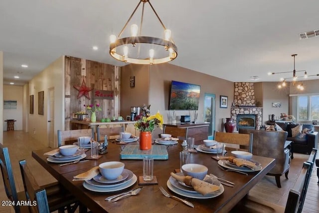 dining room with wood-type flooring, a fireplace, and an inviting chandelier