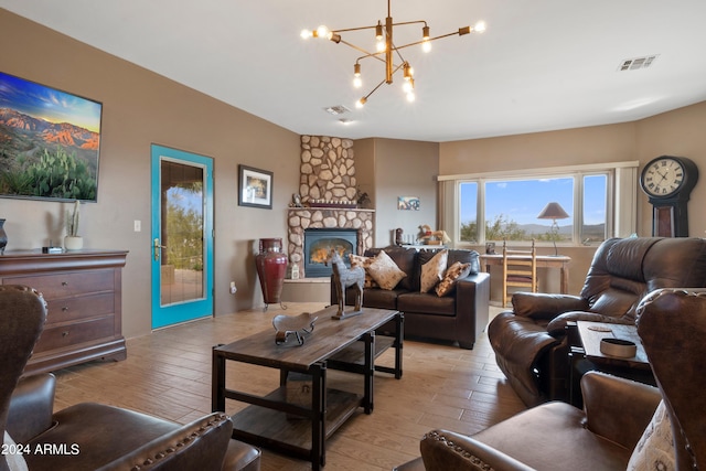 living room with a fireplace, light hardwood / wood-style floors, and a chandelier