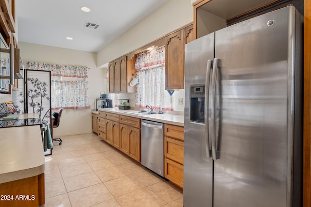 kitchen featuring appliances with stainless steel finishes, light tile patterned floors, and sink