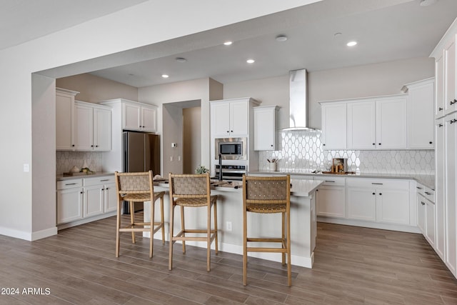 kitchen with white cabinets, stainless steel appliances, and wall chimney range hood