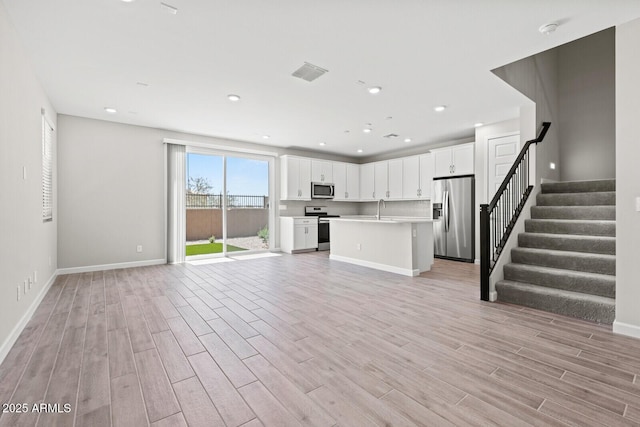 21047 N 58th Way, Phoenix, AZ 85054 - unfurnished living room featuring a sink, light wood-style floors, stairs, baseboards, and recessed lighting